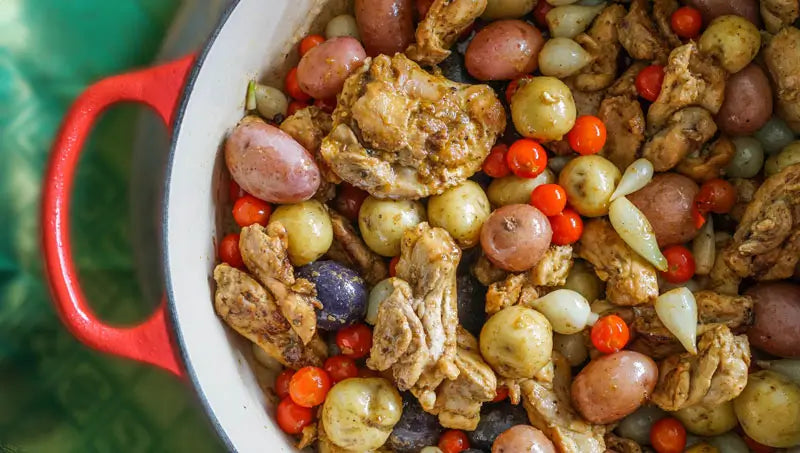 Stew pot full of Madras Curry marinated chicken thighs with potatoes and tomatoes