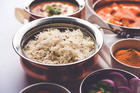 A table full of Indian dishes with the focus on a bowl of basmati pilau made in an instant pot