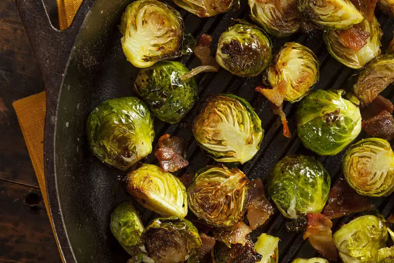 A close up of a cast iron skillet filled with roasted brussels sprouts