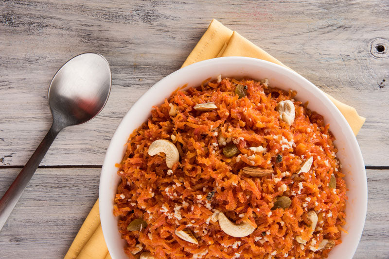 A birds eye view of a bowl of carrot halva topped with chopped pistachios.