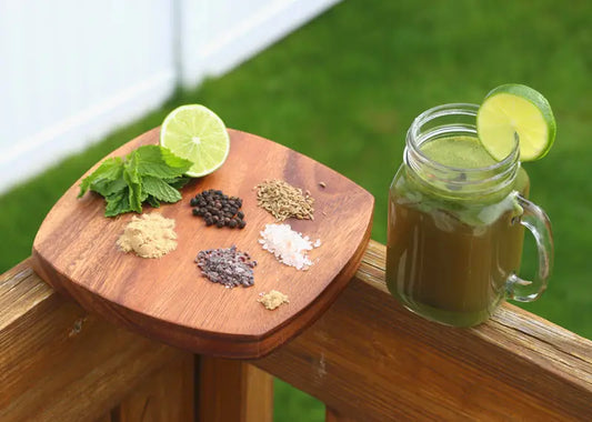 A glass of iced Jal Jeera next to a small wooden board showing all of the ingredients