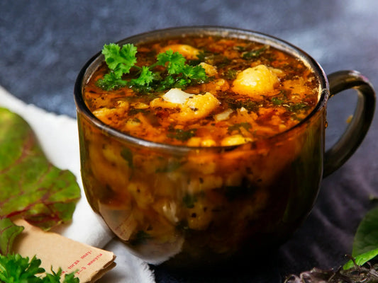 a clear bowl of sausage potato kale soup in a tomato chicken broth