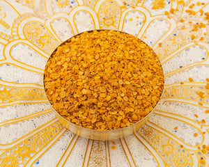 A brass bowl containing Dhana dal also known as roasted coriander seeds.