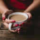 A warm cup of Ojas Hot Cocoa being held in someones hands.